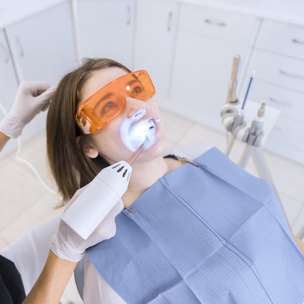 dentist-examining-patient-s-teeth-with-dental-uv-light-equipment_23-2147879110